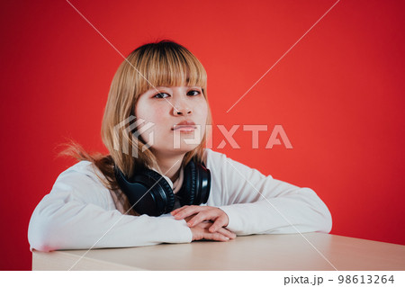 ヘッドホンを首にかける女性 98613264