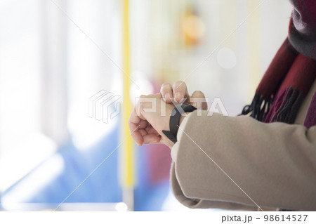 電車の中でスマートウォッチを見る女性手元 電車の中でスマートウォッチを見る女性手元 98614527