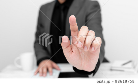 Businessman in Gray jacket sitting at table And Pointing With One Finger On Important Message. Gentleman Showing Critical Announcement. Phone on table. 98619759