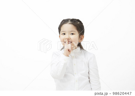 内緒のポーズをとっている白背景の子供の女の子 内緒のポーズをとっている白背景の子供の女の子 98620447