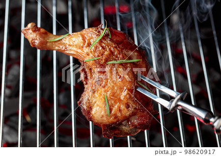 Chicken with rosemary on a grill. 98620917