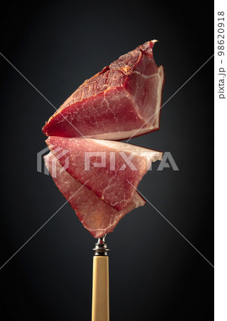 Dry-cured pork fillet on a fork. Dry-cured pork fillet on a fork. 98620918