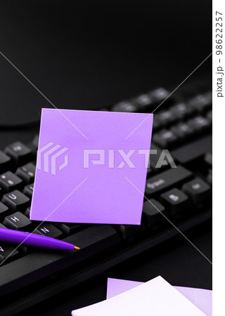 Colored sticker lying on black keyboard. Important information written over paper. Image with school supplies. Multiple Assorted Collection Office Stationery. 98622257