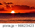 オレンジ色に染まる水平線上に沈みゆく夕日 98623423