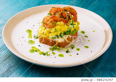 Scrambled eggs with avocado and shrimps on plate 98624297