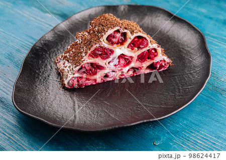 Cake from rolled pancakes with cream, cherries and grated chocolate Cake from rolled pancakes with cream, cherries and grated chocolate 98624417