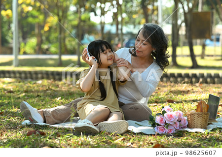 Affectionate grandmother and her sweet lovely granddaughter having picnic in park on sunny summer day Affectionate grandmother and her sweet lovely granddaughter having picnic in park on sunny summer day 98625607