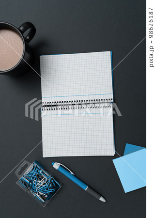 Coffee Cup Standing on Desk. Important infrormation written on paper. Different Office Supplies, Pencils, Pens, Marckers. Computer keyboard. Text on wood table. 98626187