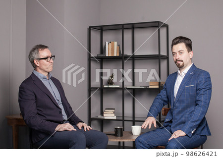 Successful businessman in eye glasses and suit discuss work with colleague in office Successful businessman in eye glasses and suit discuss work with colleague in office 98626421