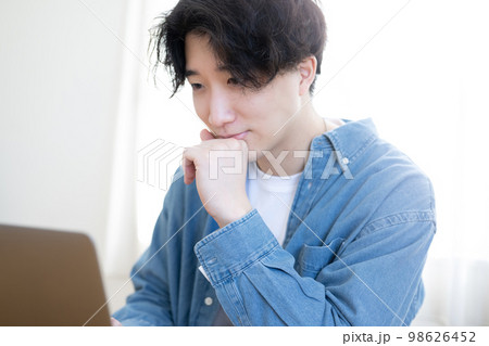 パソコンを見て微笑む男性 98626452