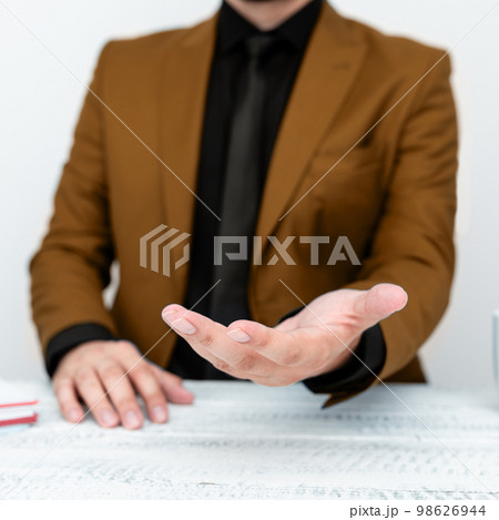Businessman in Brown jacket Holding Important Message In One Hand. Man In Suit Showing New Crutial Idea In Palm. Executive Presenting Updated Critical Information. 98626944