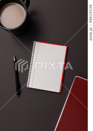 Coffee Cup Standing on Desk. Important infrormation written on paper. Different Office Supplies, Pencils, Pens, Marckers. Computer keyboard. Text on wood table. 98629336