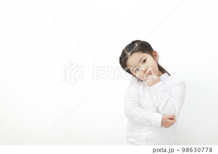 首を傾げて考えたり、悩んだりする白背景の子供の女の子 98630778