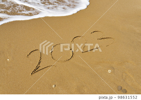 Handwritten Inscription on wet sand 2023 with sea foam and wave. Concept of fresh starts and expectations Handwritten Inscription on wet sand 2023 with sea foam and wave. Concept of fresh starts and expectations 98631552