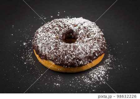 Sprinkling sugar powder on chocolate donut Sprinkling sugar powder on chocolate donut 98632226