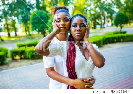two afro american women celebrating marriage in wtite dress with bright male up in summer park 98634642