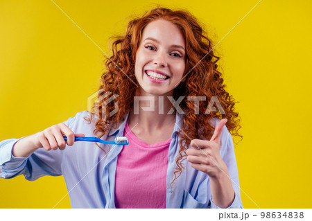redhaired ginger woman brushing teeth with toothpaste eco paste on yellow studio background 98634838