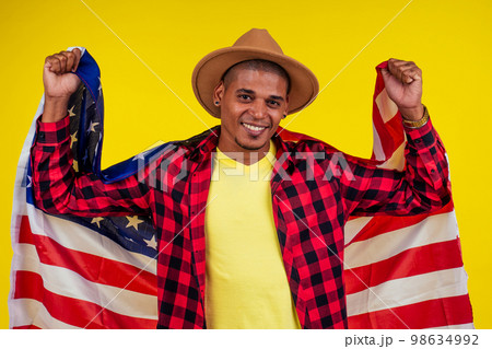 american man wrapped on flag looking at ca,era and snow-white smile 98634992