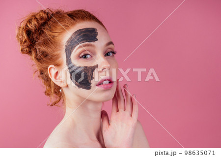 redhaired ginger young caucasian woman with natural anti acne mask on her pretty perfect face in studio pink background redhaired ginger young caucasian woman with natural anti acne mask on her pretty perfect face in studio pink background 98635071