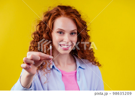 curly redhead caucasian woman use ears sticks in studio yellow background 98635209
