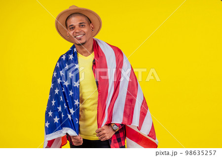 american man wrapped on flag looking at ca,era and snow-white smile american man wrapped on flag looking at ca,era and snow-white smile 98635257
