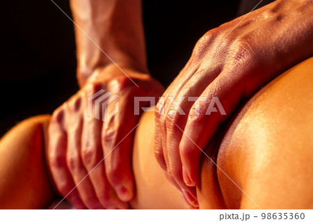 close-up masseur hands doing back massage to female client in spa center 98635360