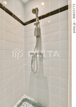 a shower with blue and white tiles on the wall next to it is a hand held shower head in the corner a shower with blue and white tiles on the wall next to it is a hand held shower head in the corner 98635773