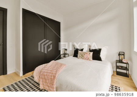 a bedroom with white walls and black closets on the wall behind the bed is a pink throw pillow that's in front a bedroom with white walls and black closets on the wall behind the bed is a pink throw pillow that's in front 98635918