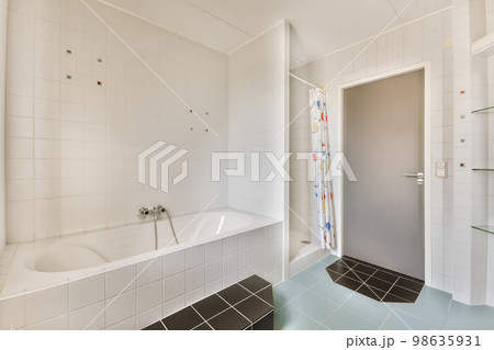 a bathroom with white tiles and blue flooring on the walls, along with a bathtub in the corner 98635931
