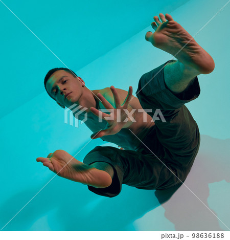 Contemporary dance style. Young artistic man dancing contemp, experimental dance over blue studio background. Emotional 98636188