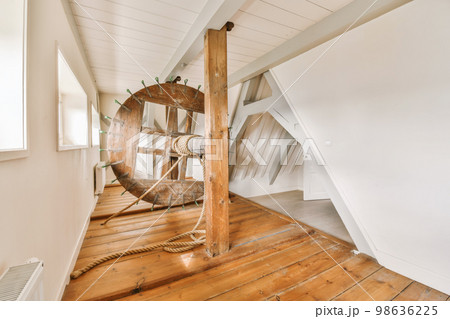 a room with wood flooring and an old clock on the wall next to it is a ladder that has been used as a 98636225
