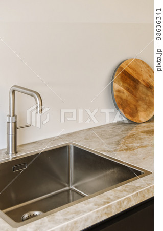 a kitchen sink with a wooden cutting board on the wall above it and a round mirror in the corner next to the sink 98636341