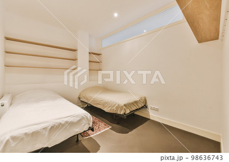 a small bedroom with two beds and shelves on the wall behind it, there is a window that looks out to the outside a small bedroom with two beds and shelves on the wall behind it, there is a window that looks out to the outside 98636743