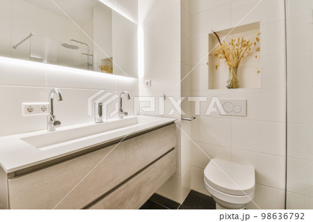 a modern bathroom with white walls and black flooring the sink is in front of the mirror on the wall 98636792