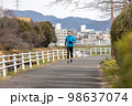 川沿いの遊歩道で趣味のジョギングをする一人の中高年男性 98637074