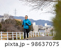 川沿いの遊歩道で趣味のジョギングをする一人の中高年男性 98637075