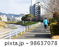 川沿いの遊歩道で趣味のジョギングをする一人の中高年男性 98637078