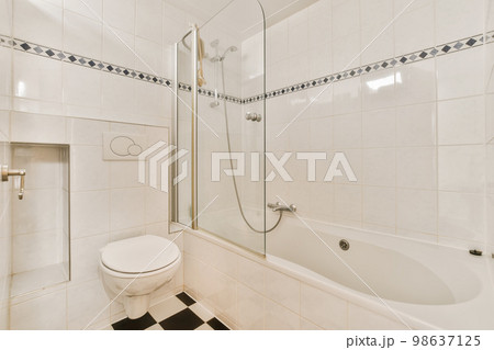 a white bathroom with black and white tiles on the floor, shower stall and toilet in the corner of the room a white bathroom with black and white tiles on the floor, shower stall and toilet in the corner of the room 98637125