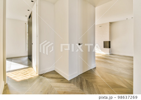 an empty room with white walls and wood flooring in the center of the room, there is a door leading to another room 98637269