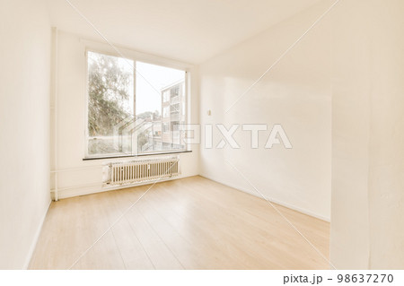 an empty room with white walls and wood flooring on the right, there is a large window to the left 98637270