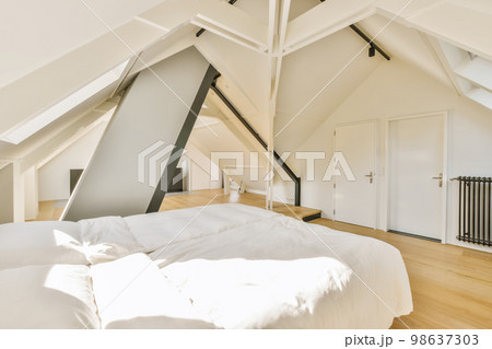 a bed in a bedroom with white sheets and pillows on top of the bed is an attic - style loft 98637303