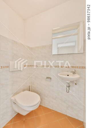 a bathroom with tile flooring and white tiles on the walls, there is a mirror above the toilet bowl 98637342