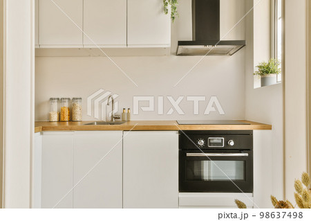 a kitchen with white cupboards and wood counter tops on the wall above it is an oven, sink, dishwasher and microwave 98637498