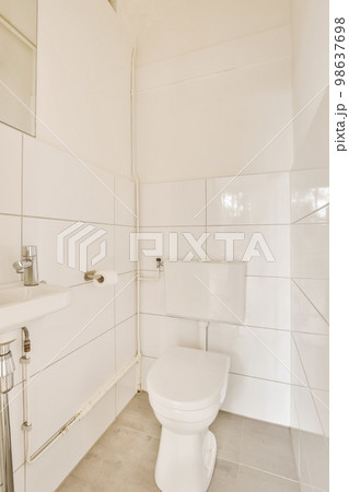 a bathroom with white tiles on the walls, and a toilet in the corner next to the sink is visible 98637698
