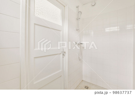 a bathroom with white tiles on the floor and shower stall door open to show how it's supposed to be 98637737