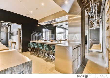 Contemporary minimalist style interior design of light studio apartment with wooden table and chairs in dining zone between open kitchen and living room with white walls and parquet floor 98637792