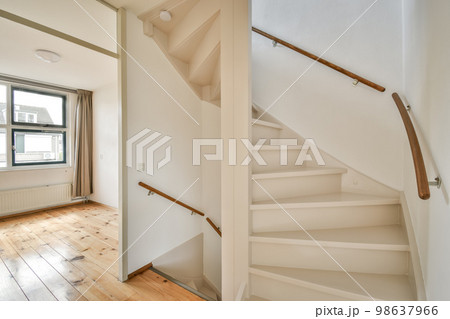 an empty room with wood flooring and white painted staircase leading up to the second floor in a home for sale 98637966