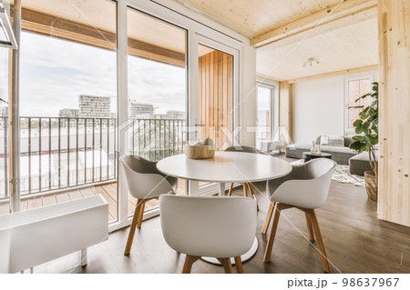 Home interior design of modern loft apartment with open kitchen in minimalist style and spacious dining zone with table and chairs 98637967