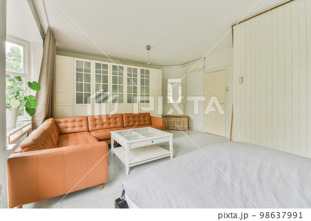 a living room with an orange couch and white bed in the photo is taken from the front door to the bedroom 98637991