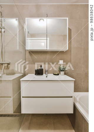 Sinks with mirrors and shower box with glass door in modern bathroom with white tiled walls 98638042